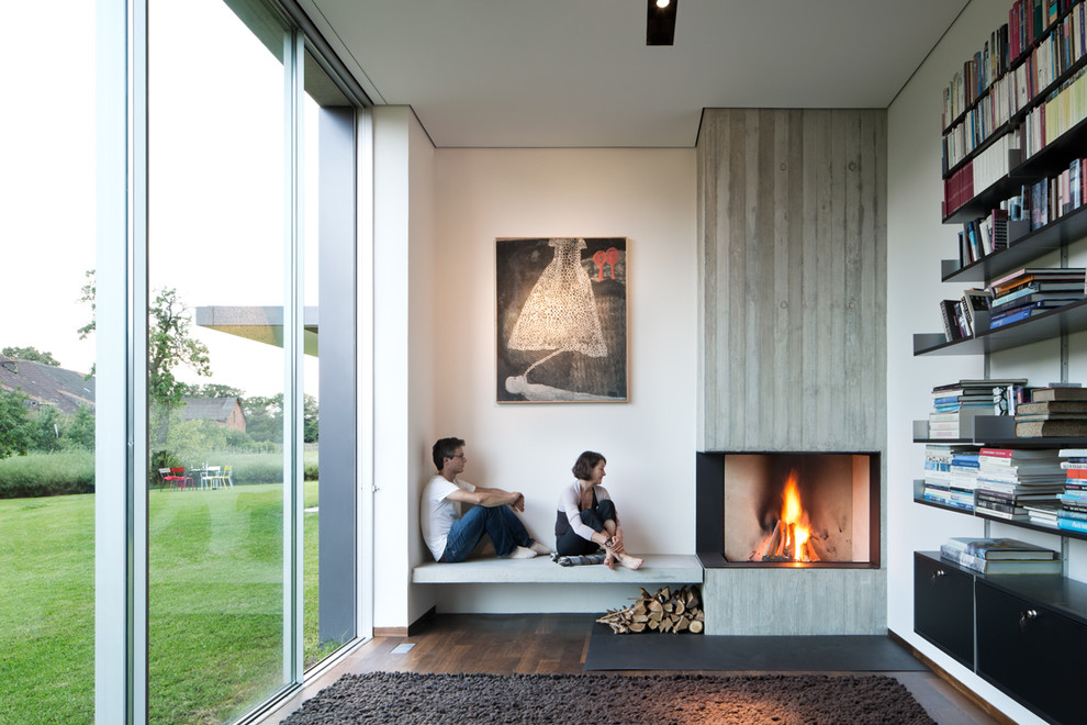 Medium sized contemporary enclosed living room in Berlin with a corner fireplace, a reading nook, white walls, dark hardwood flooring and a concrete fireplace surround.