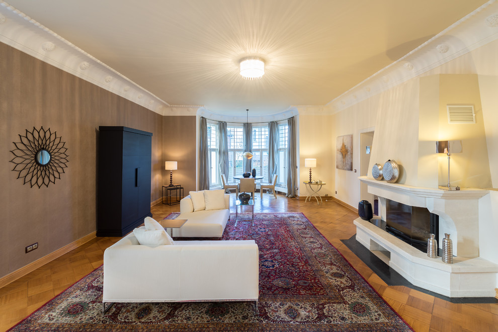 Cette photo montre une grande salle de séjour tendance ouverte avec un sol en bois brun, une cheminée standard, un manteau de cheminée en pierre, aucun téléviseur et un mur multicolore.