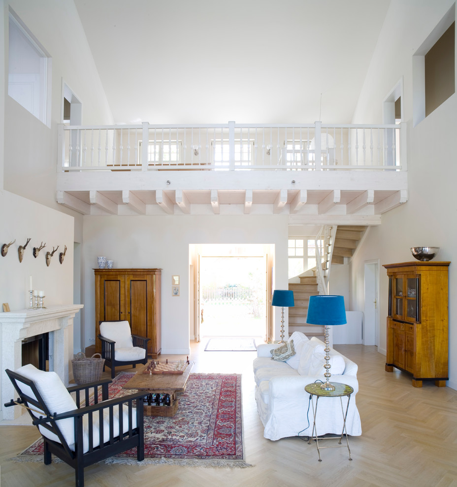 Стильный дизайн: большая открытая гостиная комната в стиле кантри с белыми стенами, светлым паркетным полом и стандартным камином - последний тренд