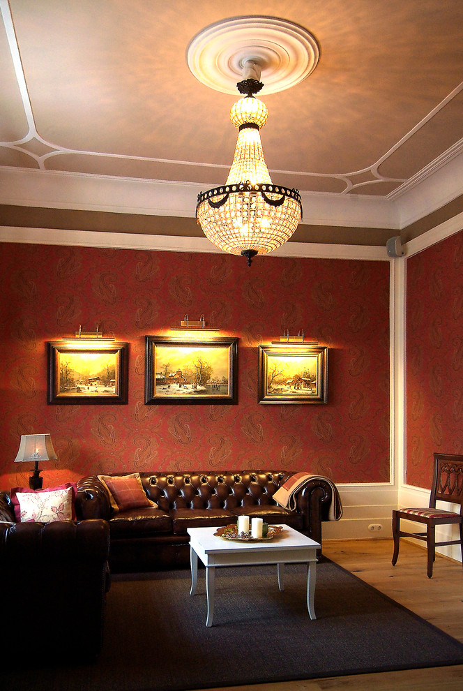 This is an example of a large traditional formal enclosed living room in Dusseldorf with red walls, light hardwood flooring, a wood burning stove, a wooden fireplace surround and no tv.