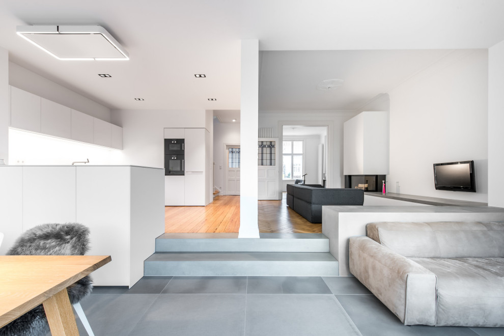 Mittelgroßes, Offenes Modernes Wohnzimmer mit weißer Wandfarbe, hellem Holzboden, Eckkamin, Kaminumrandung aus Metall und TV-Wand in Hamburg