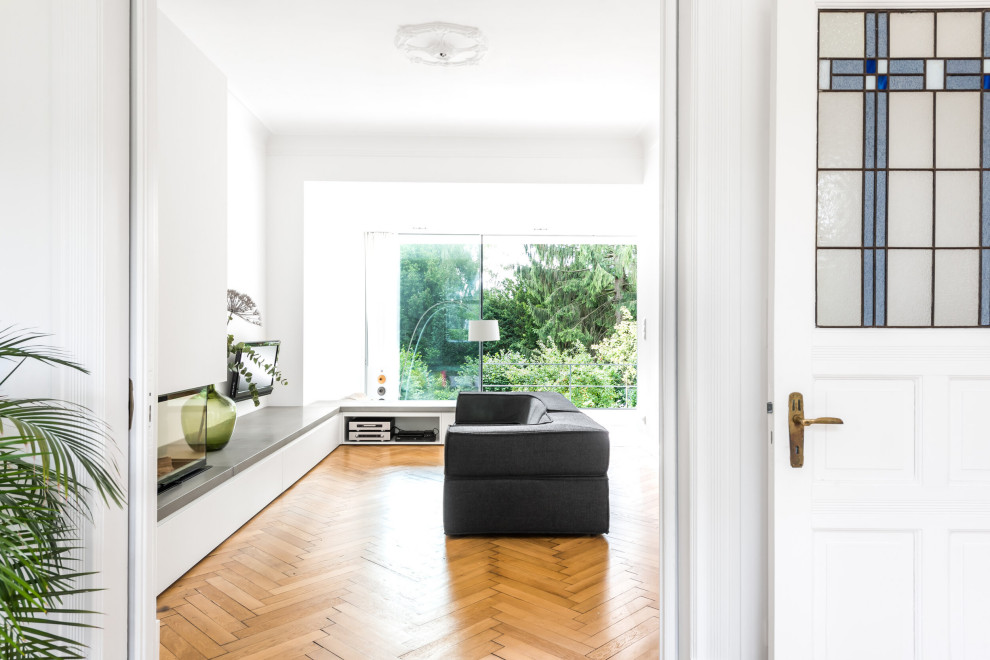 Idées déco pour un salon moderne de taille moyenne et ouvert avec un mur blanc, parquet clair, une cheminée d'angle, un manteau de cheminée en métal et un téléviseur fixé au mur.