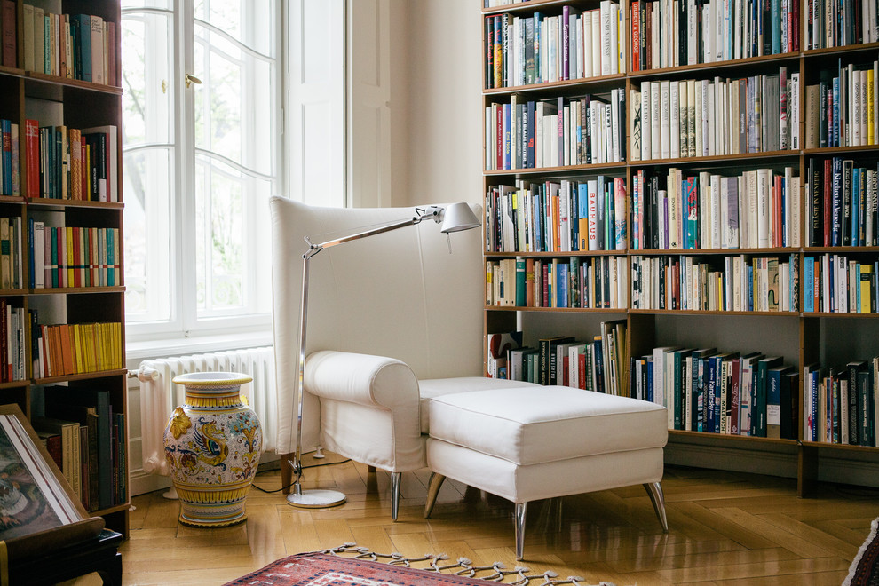 Diseño de sala de estar con biblioteca cerrada actual de tamaño medio con paredes beige y suelo de madera en tonos medios