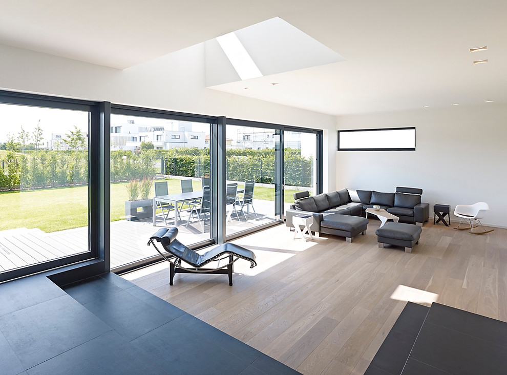 Large contemporary open plan living room in Cologne with white walls, medium hardwood flooring and no fireplace.