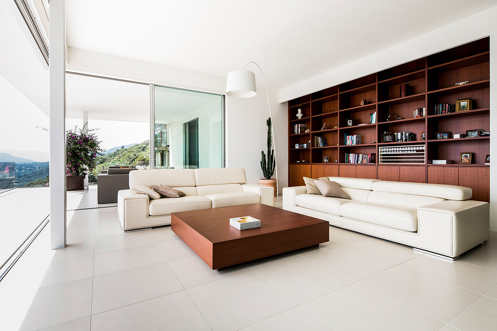 Immagine di un soggiorno minimalista di medie dimensioni e stile loft con libreria, pareti bianche, nessun camino e pavimento bianco