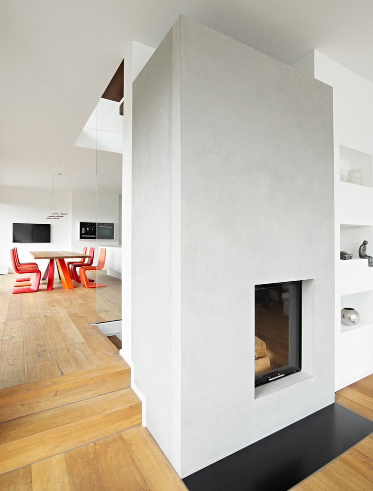 Idée de décoration pour un salon design fermé avec une cheminée standard, un manteau de cheminée en plâtre, un mur gris et un sol en bois brun.