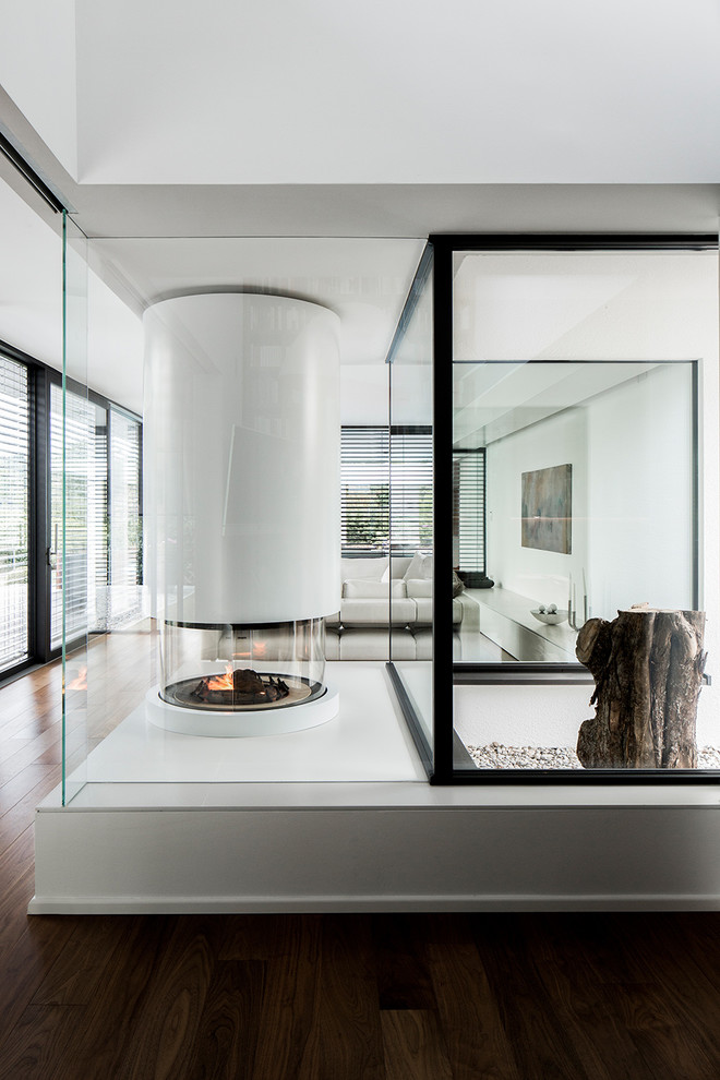 Esempio di un grande soggiorno minimalista stile loft con sala formale, pareti bianche, parquet scuro, stufa a legna, cornice del camino in metallo e pavimento marrone