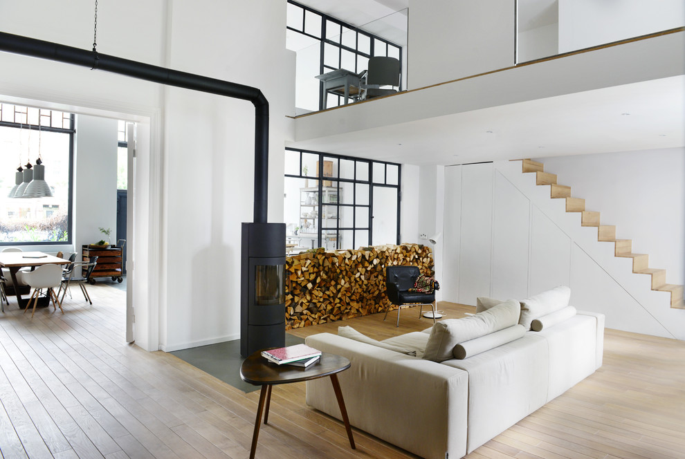 Diseño de salón escandinavo de tamaño medio sin televisor con paredes blancas, suelo de madera clara y estufa de leña
