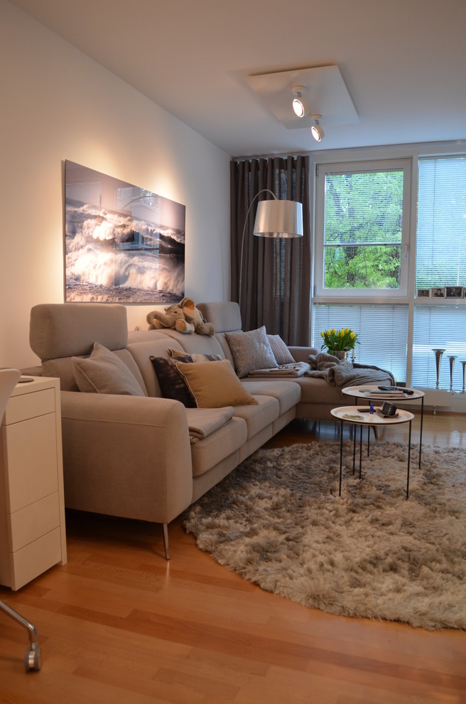 Immagine di un piccolo soggiorno nordico aperto con pareti bianche, pavimento in legno massello medio e TV a parete
