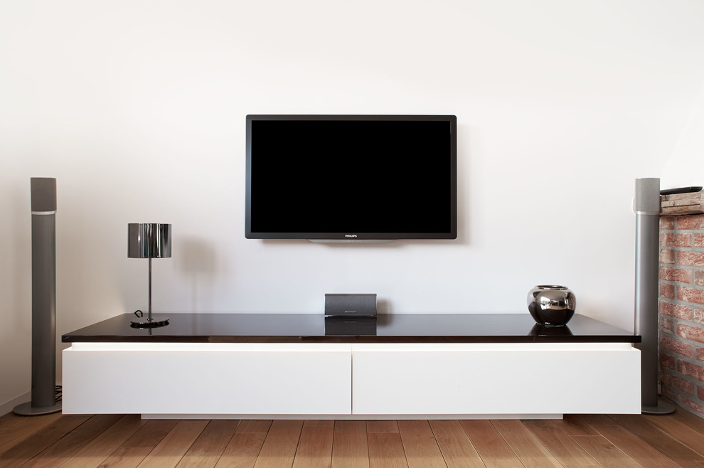 Réalisation d'une salle de séjour design avec un mur blanc, un sol en bois brun et un téléviseur fixé au mur.