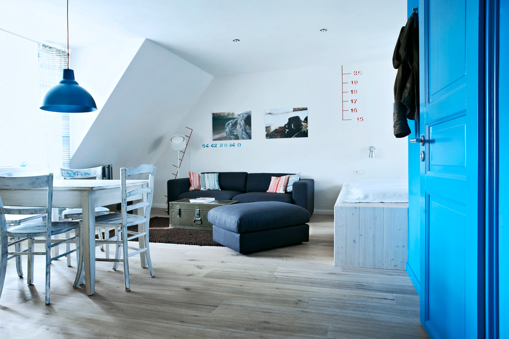 Imagen de salón para visitas abierto costero pequeño sin chimenea con paredes blancas, suelo de madera clara y televisor independiente