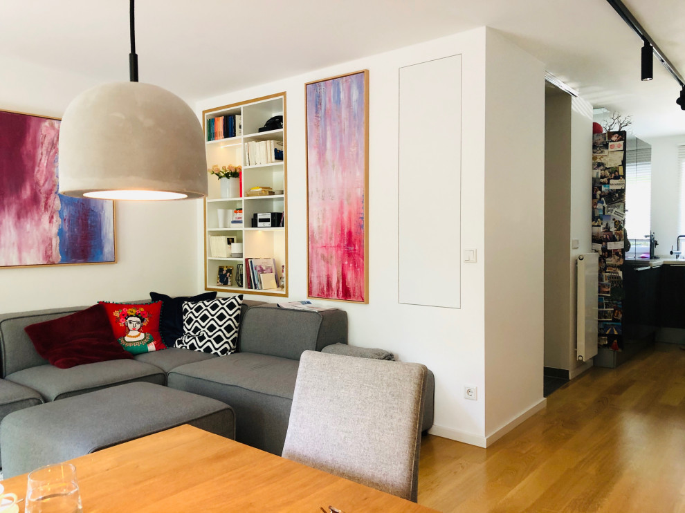 Imagen de salón abierto contemporáneo pequeño con paredes beige, suelo de madera en tonos medios y televisor colgado en la pared