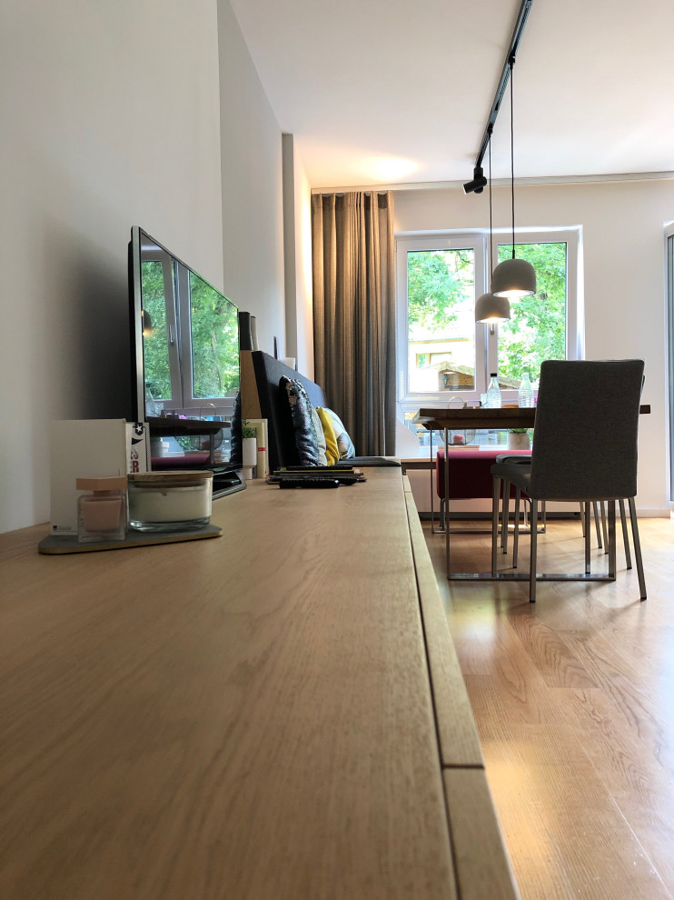 Kleines, Offenes Modernes Wohnzimmer mit beiger Wandfarbe, braunem Holzboden und TV-Wand in München