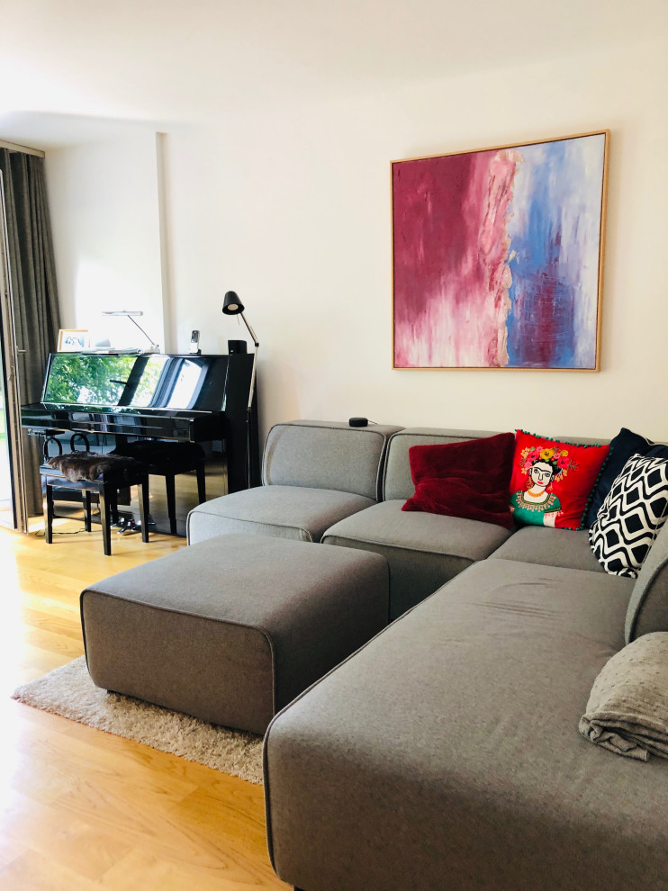 Immagine di un piccolo soggiorno contemporaneo aperto con pareti beige, pavimento in legno massello medio e TV a parete