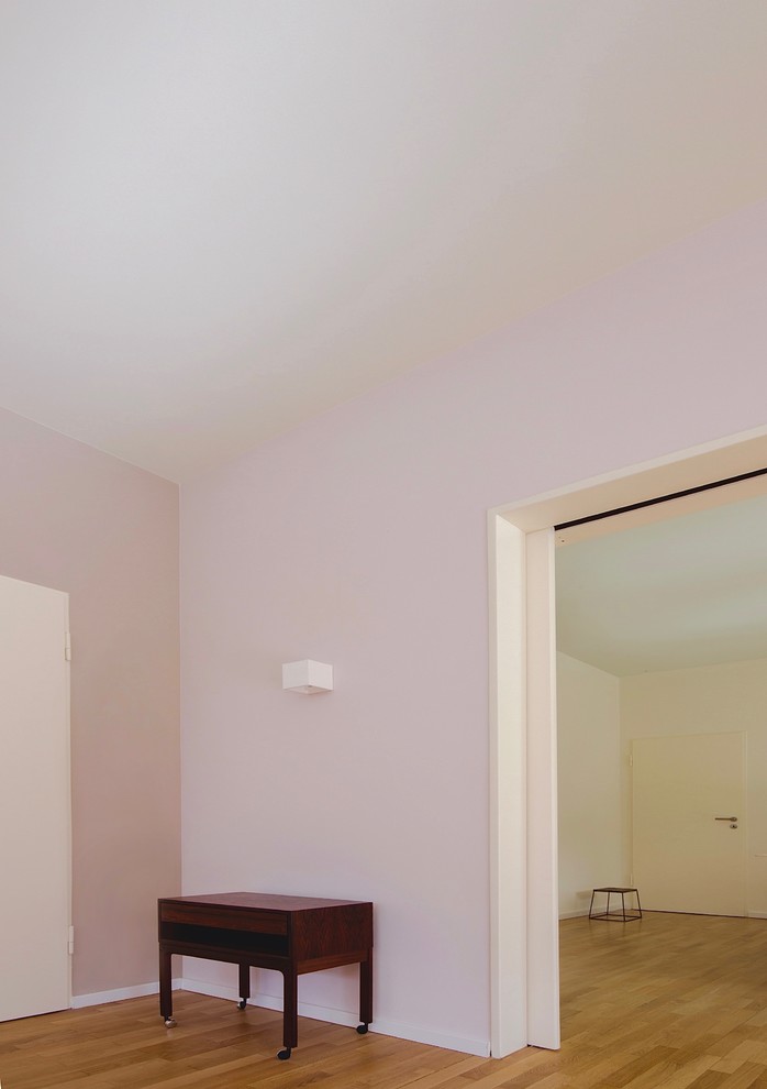 Ejemplo de salón con barra de bar abierto moderno grande con paredes rosas, suelo de madera en tonos medios, televisor colgado en la pared y suelo marrón