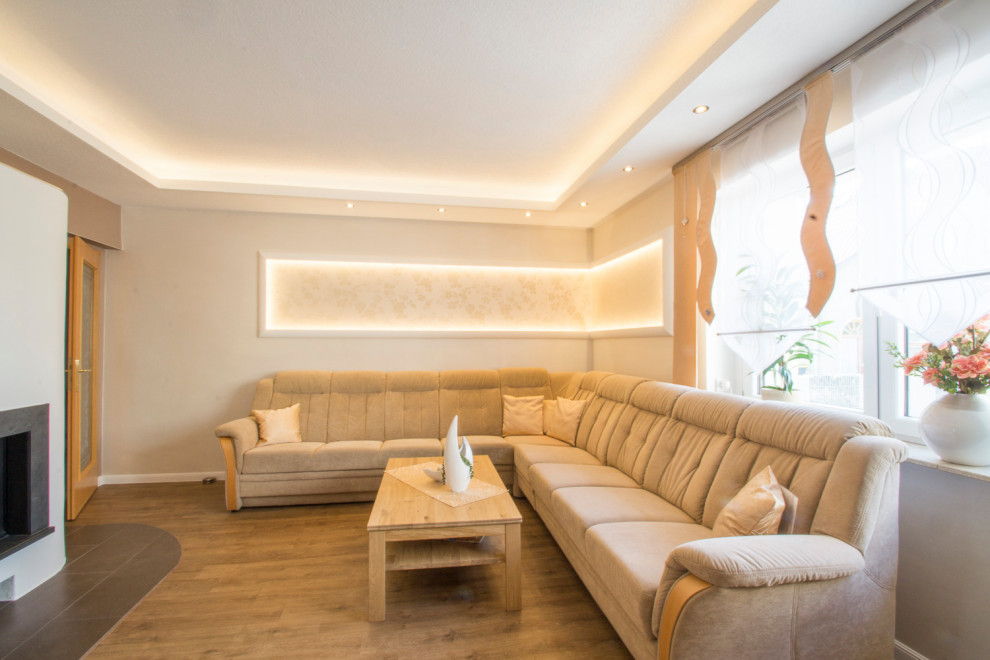 Cette image montre une salle de séjour traditionnelle de taille moyenne avec un mur gris, un sol en vinyl, un poêle à bois, un manteau de cheminée en plâtre, un sol marron, un plafond décaissé et du papier peint.