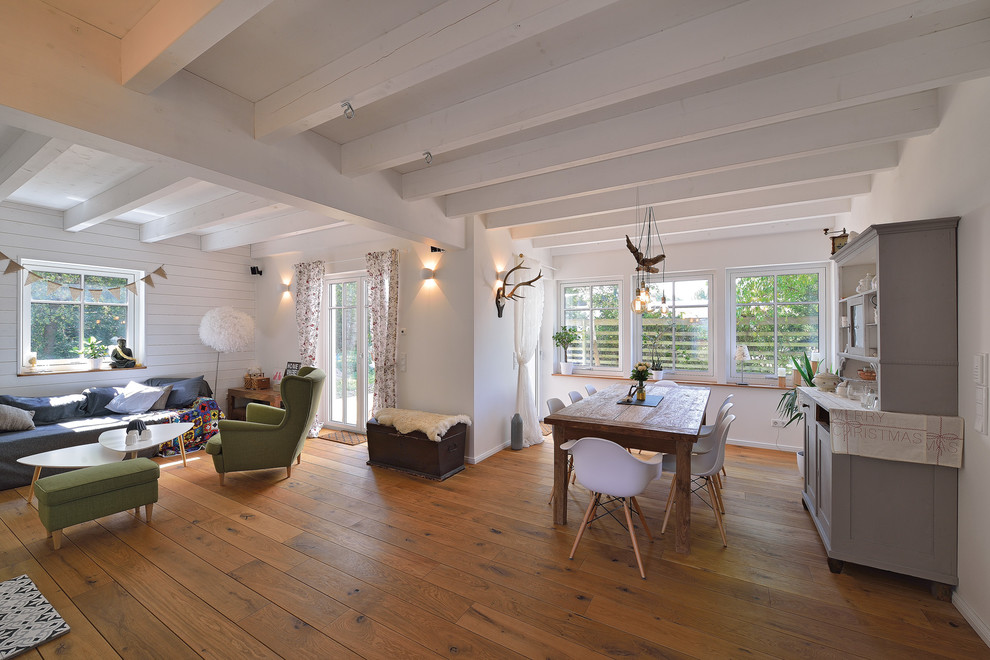 Modelo de salón abierto escandinavo grande con paredes blancas y suelo de madera en tonos medios