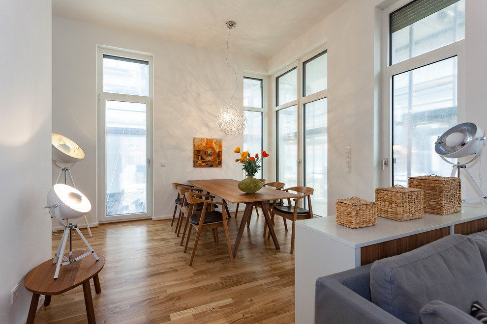 Großes, Repräsentatives, Fernseherloses, Offenes Modernes Wohnzimmer ohne Kamin mit weißer Wandfarbe, braunem Holzboden und braunem Boden in Leipzig