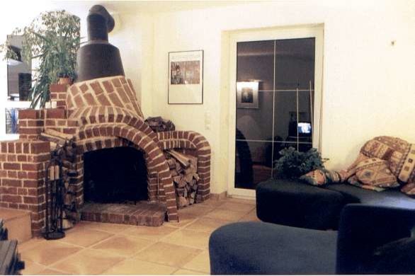 Imagen de sala de estar abierta de estilo de casa de campo con paredes blancas, suelo de baldosas de terracota, estufa de leña, marco de chimenea de ladrillo y suelo beige