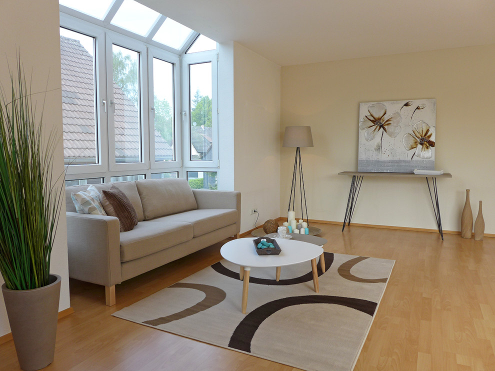 Foto de sala de estar cerrada actual de tamaño medio sin chimenea y televisor con paredes beige y suelo de madera clara
