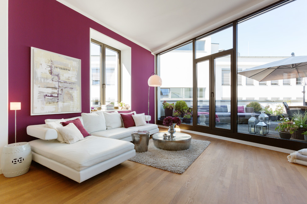Offenes Modernes Wohnzimmer mit lila Wandfarbe und braunem Holzboden in Köln