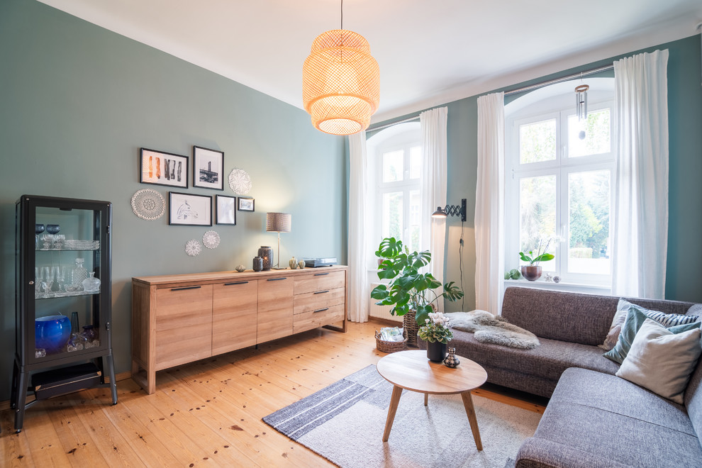 Großes Nordisches Wohnzimmer mit grüner Wandfarbe, braunem Holzboden und braunem Boden in Berlin