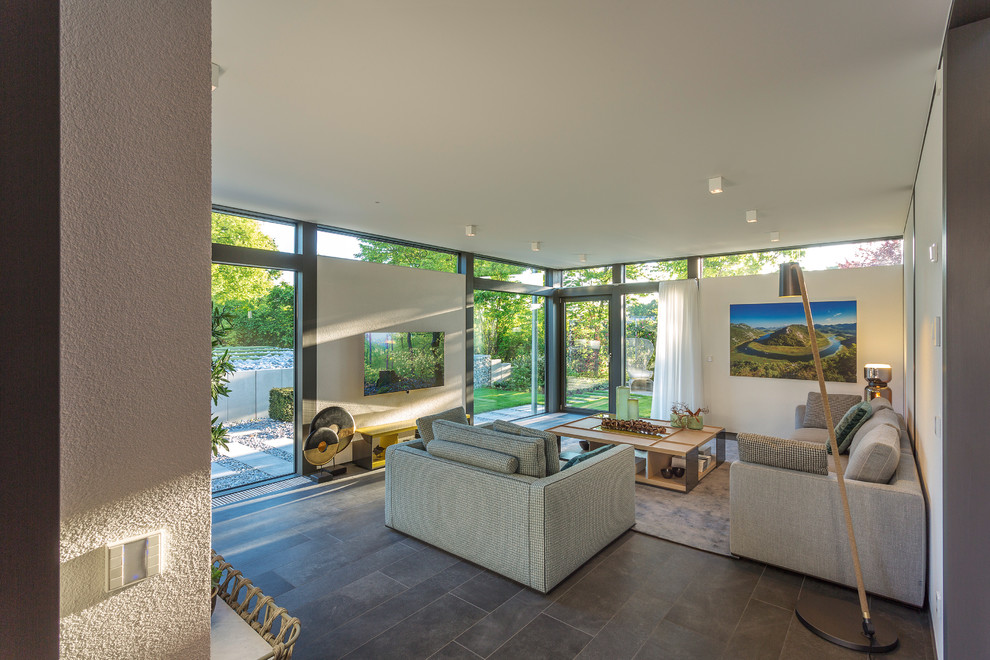 Foto di un grande soggiorno minimal stile loft con pareti bianche, TV a parete, pavimento grigio e pavimento con piastrelle in ceramica