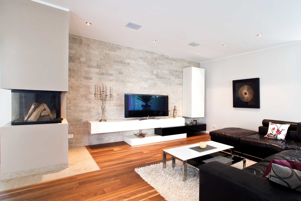 Cette photo montre une salle de séjour tendance ouverte et de taille moyenne avec un mur blanc, un sol en bois brun, un manteau de cheminée en plâtre, un téléviseur indépendant et une cheminée double-face.