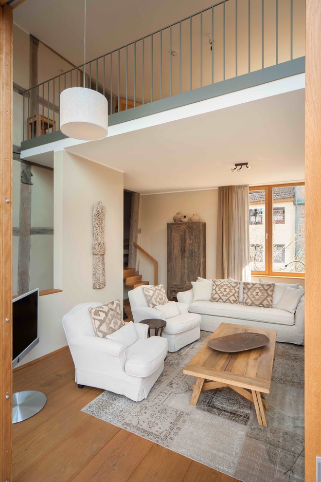 Großes, Offenes Klassisches Wohnzimmer ohne Kamin mit weißer Wandfarbe, braunem Holzboden und freistehendem TV in Sonstige