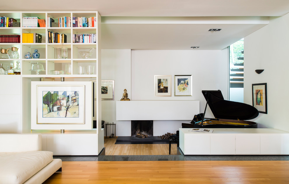 Offenes Modernes Wohnzimmer mit weißer Wandfarbe, hellem Holzboden und Kamin in München