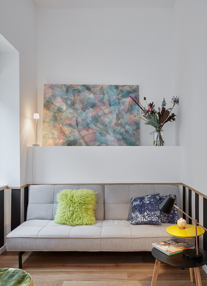 Modelo de sala de estar abierta actual pequeña sin chimenea y televisor con paredes blancas, suelo de madera en tonos medios y suelo marrón