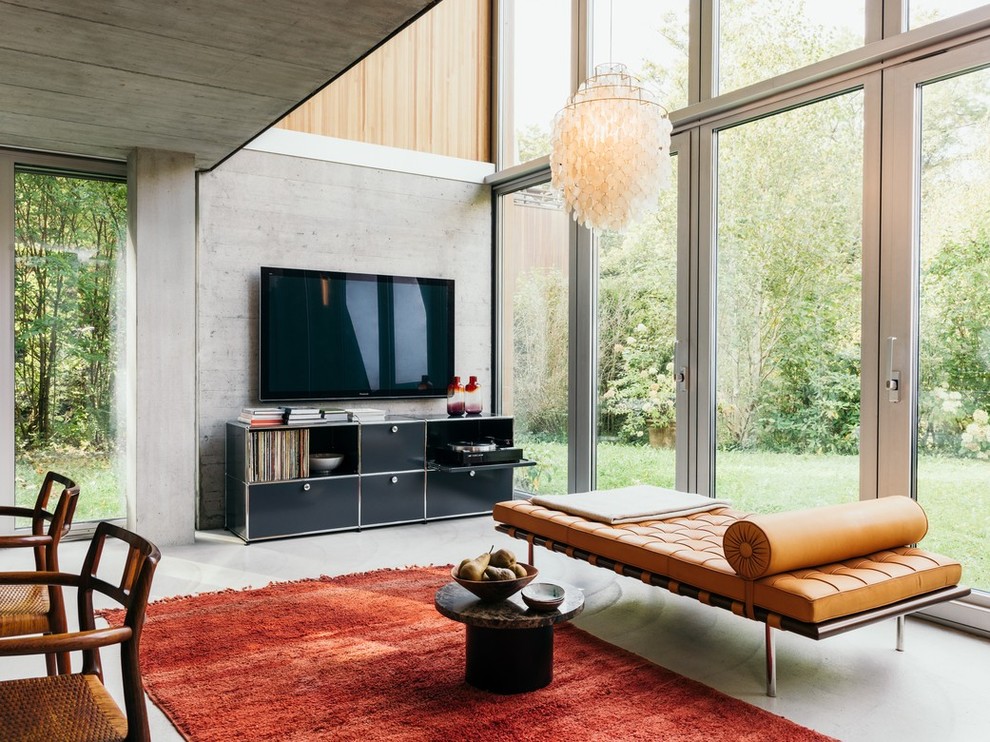 Источник вдохновения для домашнего уюта: открытая гостиная комната среднего размера в современном стиле с серыми стенами, бетонным полом, телевизором на стене и серым полом
