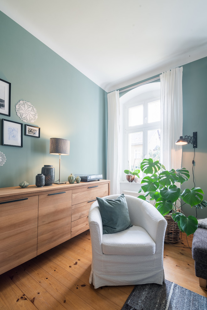 Cette image montre une salle de séjour nordique de taille moyenne avec un mur vert et un sol en bois brun.