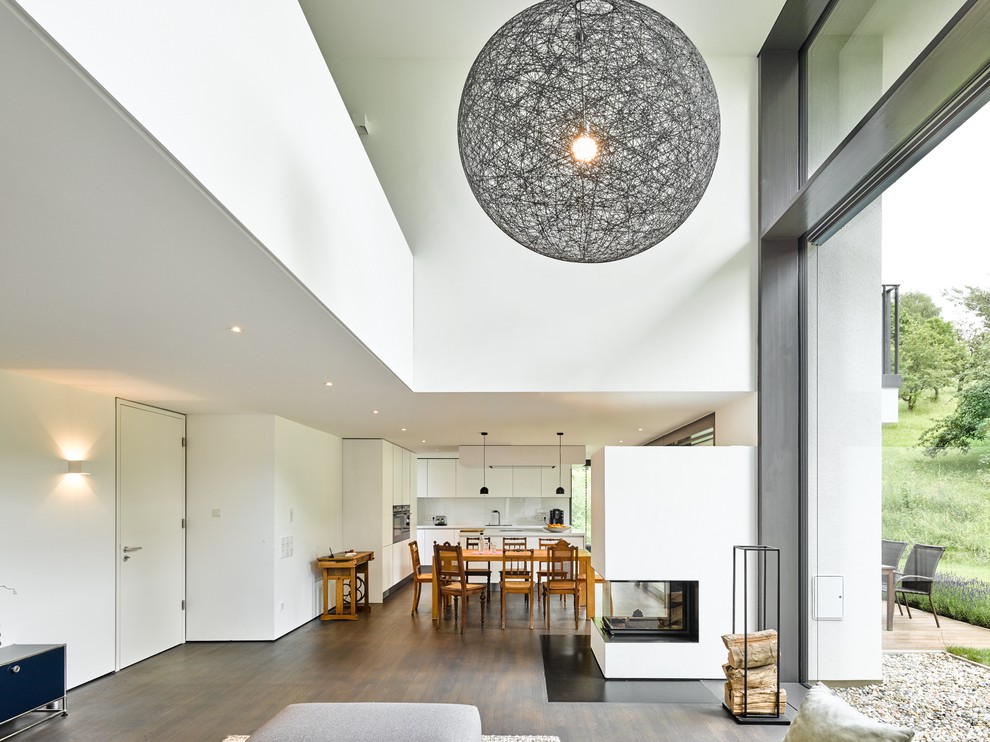 Exempel på ett mycket stort modernt loftrum, med ett finrum, vita väggar, målat trägolv, en dubbelsidig öppen spis, en spiselkrans i gips och brunt golv