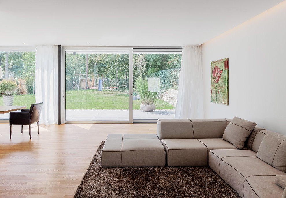 Imagen de sala de estar abierta moderna grande con suelo de madera clara