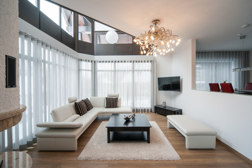 Foto di un grande soggiorno design aperto con pareti bianche, pavimento in legno massello medio e porta TV ad angolo