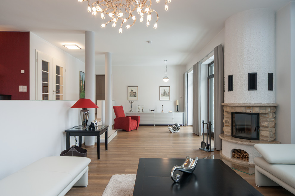 Modelo de sala de estar abierta contemporánea extra grande con paredes blancas, suelo de madera en tonos medios y todas las chimeneas