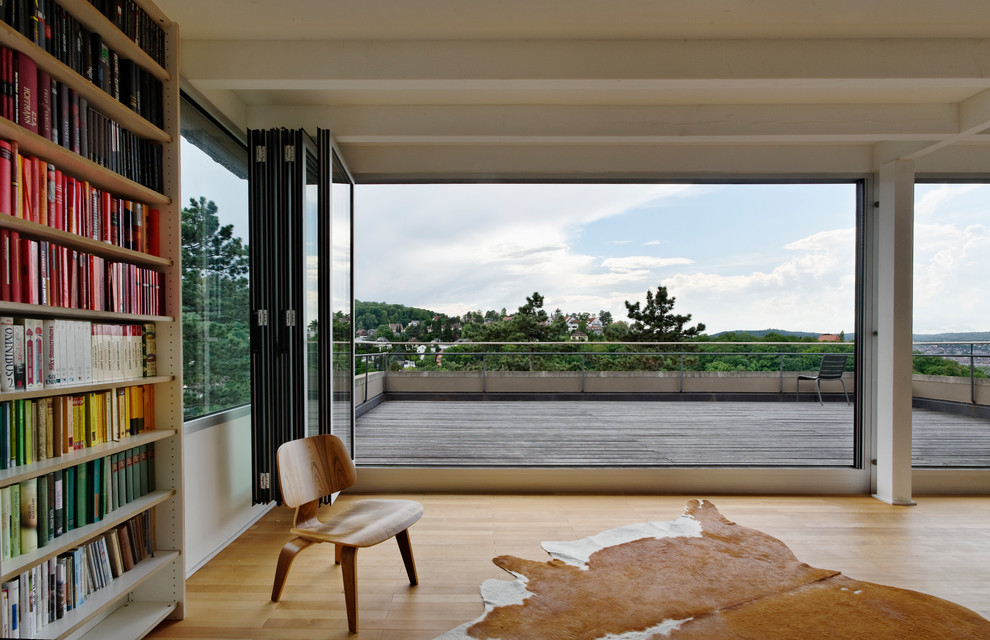 Immagine di un soggiorno minimalista aperto con libreria e pavimento in legno massello medio