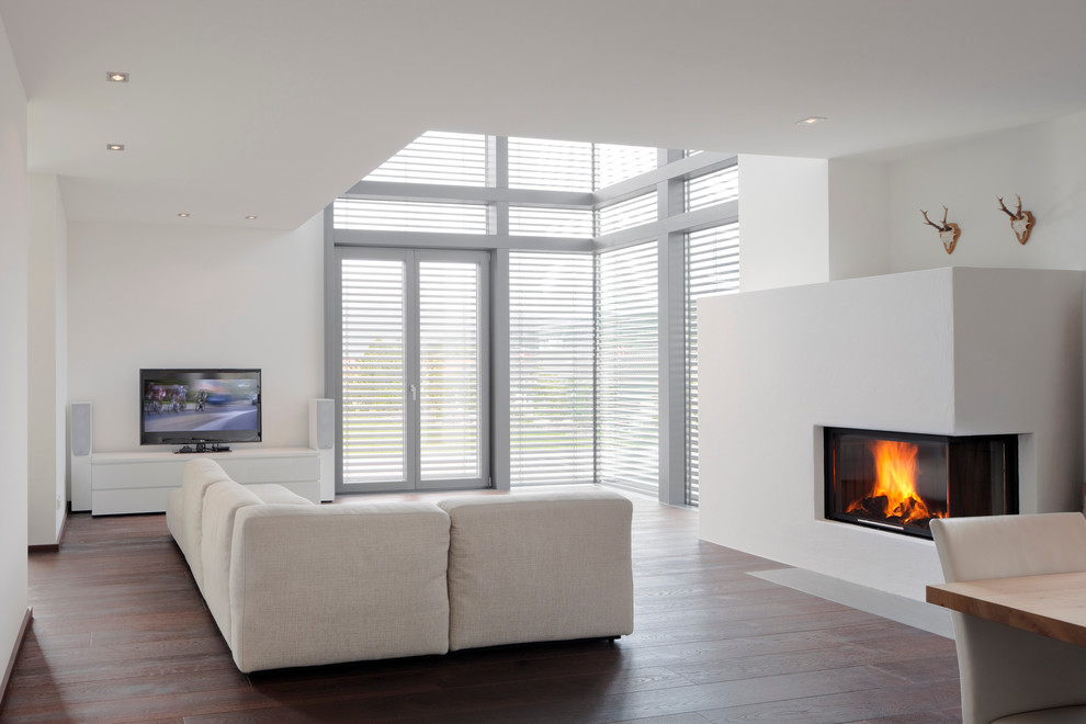 Inspiration for a large contemporary formal enclosed living room in Munich with white walls, dark hardwood flooring, a ribbon fireplace, a plastered fireplace surround and a freestanding tv.