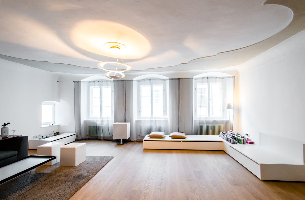 Diseño de salón escandinavo con paredes blancas, suelo de madera en tonos medios y pared multimedia
