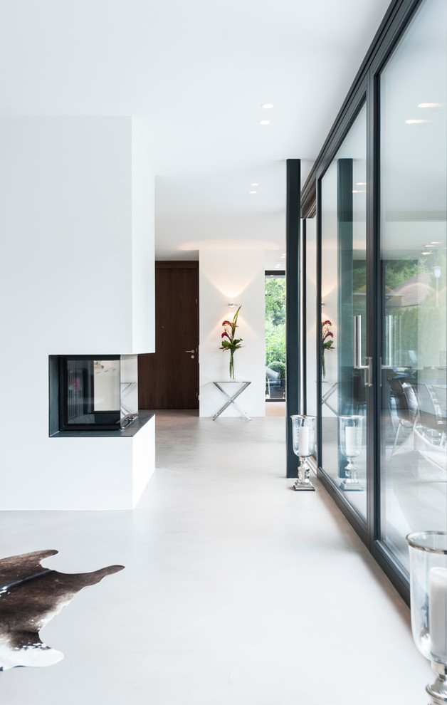 This is an example of a medium sized modern formal open plan living room in Munich with white walls, concrete flooring, a corner fireplace, a stone fireplace surround and grey floors.