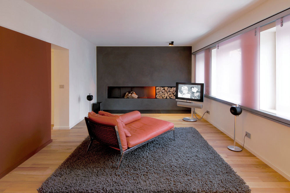 Стильный дизайн: открытая гостиная комната среднего размера в современном стиле с черными стенами, стандартным камином, фасадом камина из штукатурки и отдельно стоящим телевизором - последний тренд