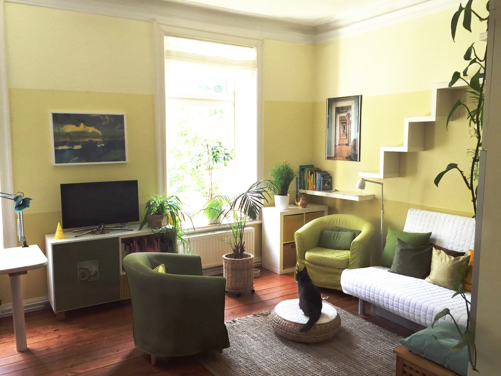 Kleines Modernes Wohnzimmer mit gelber Wandfarbe und braunem Holzboden in Hamburg