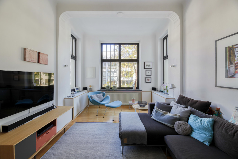Geräumiges, Offenes Modernes Wohnzimmer mit weißer Wandfarbe, hellem Holzboden, freistehendem TV, braunem Boden und gewölbter Decke in Köln