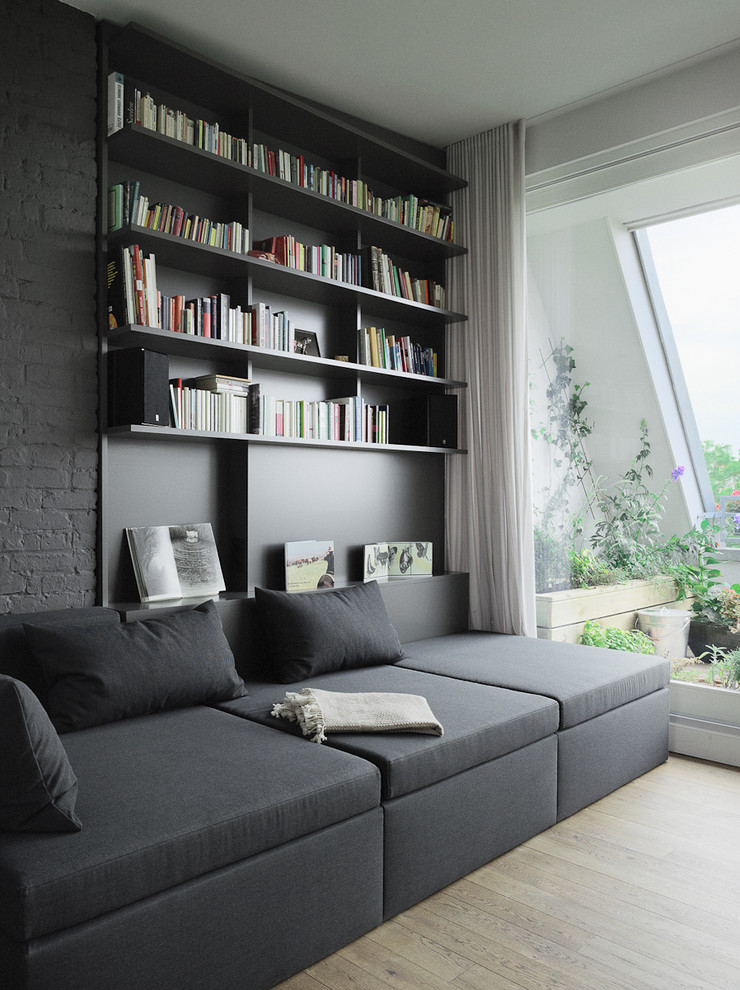 Modelo de sala de estar con biblioteca actual de tamaño medio con paredes grises y suelo de madera clara