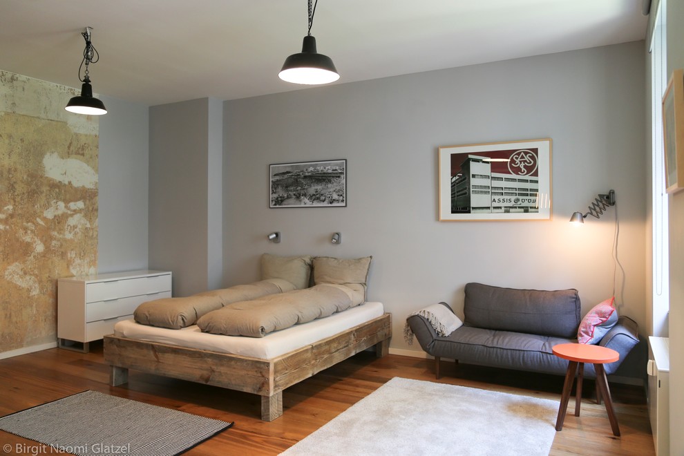 Foto de salón tipo loft urbano pequeño con paredes grises y suelo de madera en tonos medios