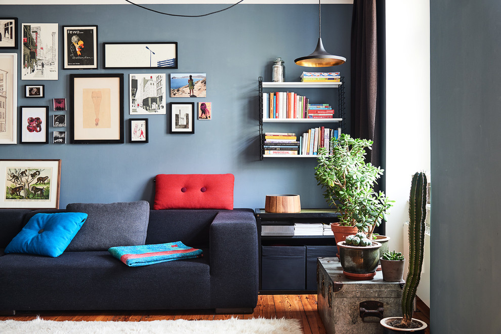 Mittelgroßes, Fernseherloses, Abgetrenntes Modernes Wohnzimmer ohne Kamin mit blauer Wandfarbe und braunem Holzboden in Berlin