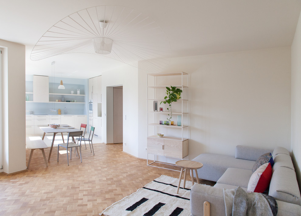 Mittelgroßes, Fernseherloses, Offenes Skandinavisches Wohnzimmer ohne Kamin mit weißer Wandfarbe, braunem Holzboden und braunem Boden in Berlin