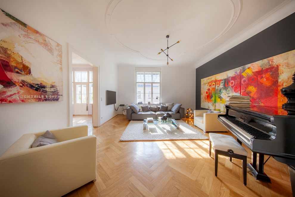 Large bohemian enclosed games room in Munich with black walls, medium hardwood flooring, no fireplace, a wall mounted tv, brown floors and a music area.