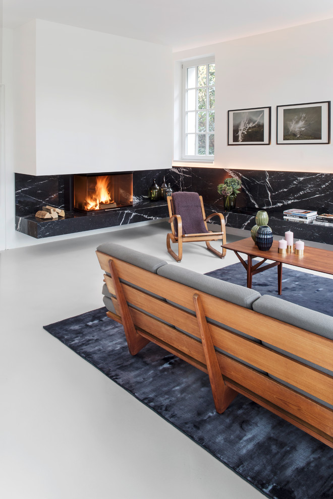 This is an example of a large scandinavian games room in Berlin with a ribbon fireplace, white walls and a stone fireplace surround.